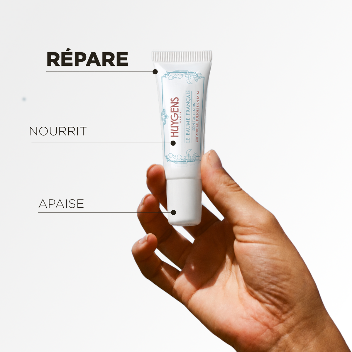 Tube du baume tenu à la main : il répare, nourrit et apaise