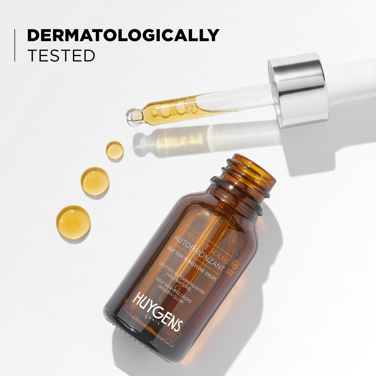 Open bottle and golden drops, dermatologically tested